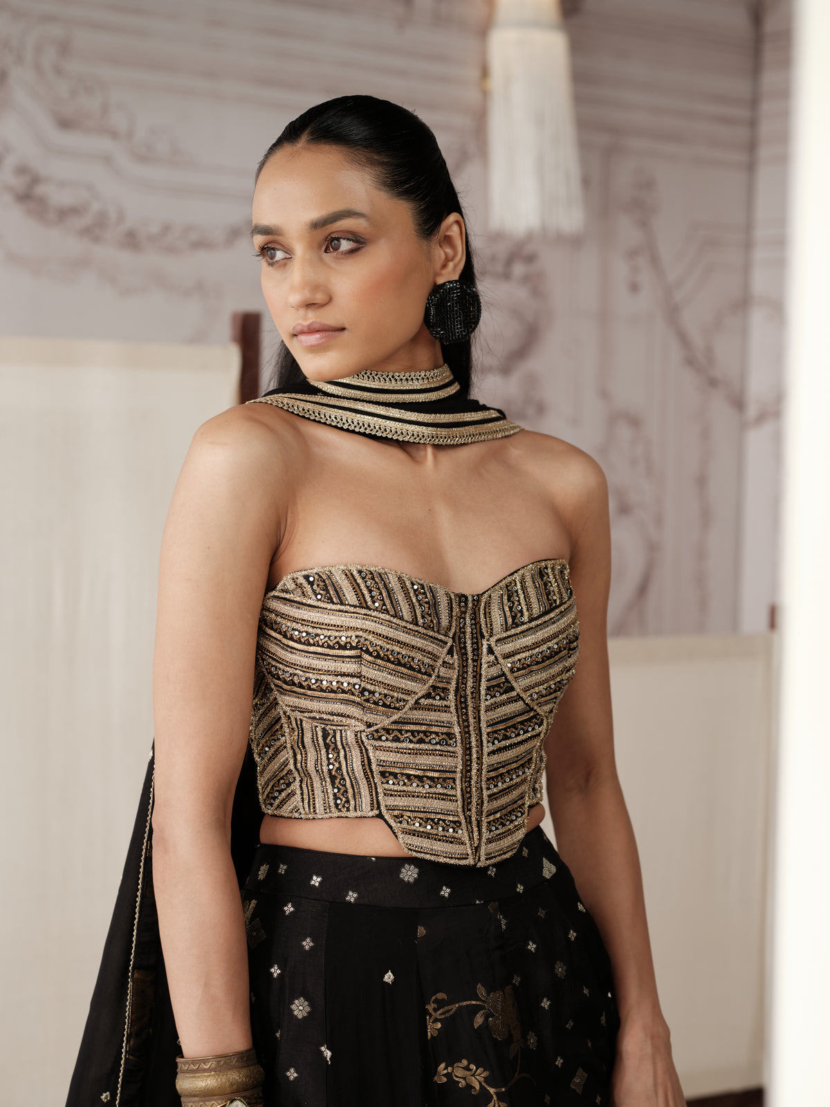 Black And Gold Banarasi lehenga choli featuring intricate gold embroidery, delicate motifs and a richly detailed border, paired with a matching embellished dupatta. It also features a modern strapless corset blouse.