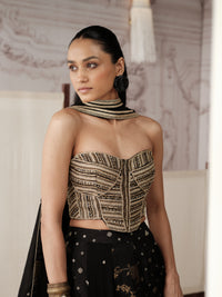 Black And Gold Banarasi lehenga choli featuring intricate gold embroidery, delicate motifs and a richly detailed border, paired with a matching embellished dupatta. It also features a modern strapless corset blouse.