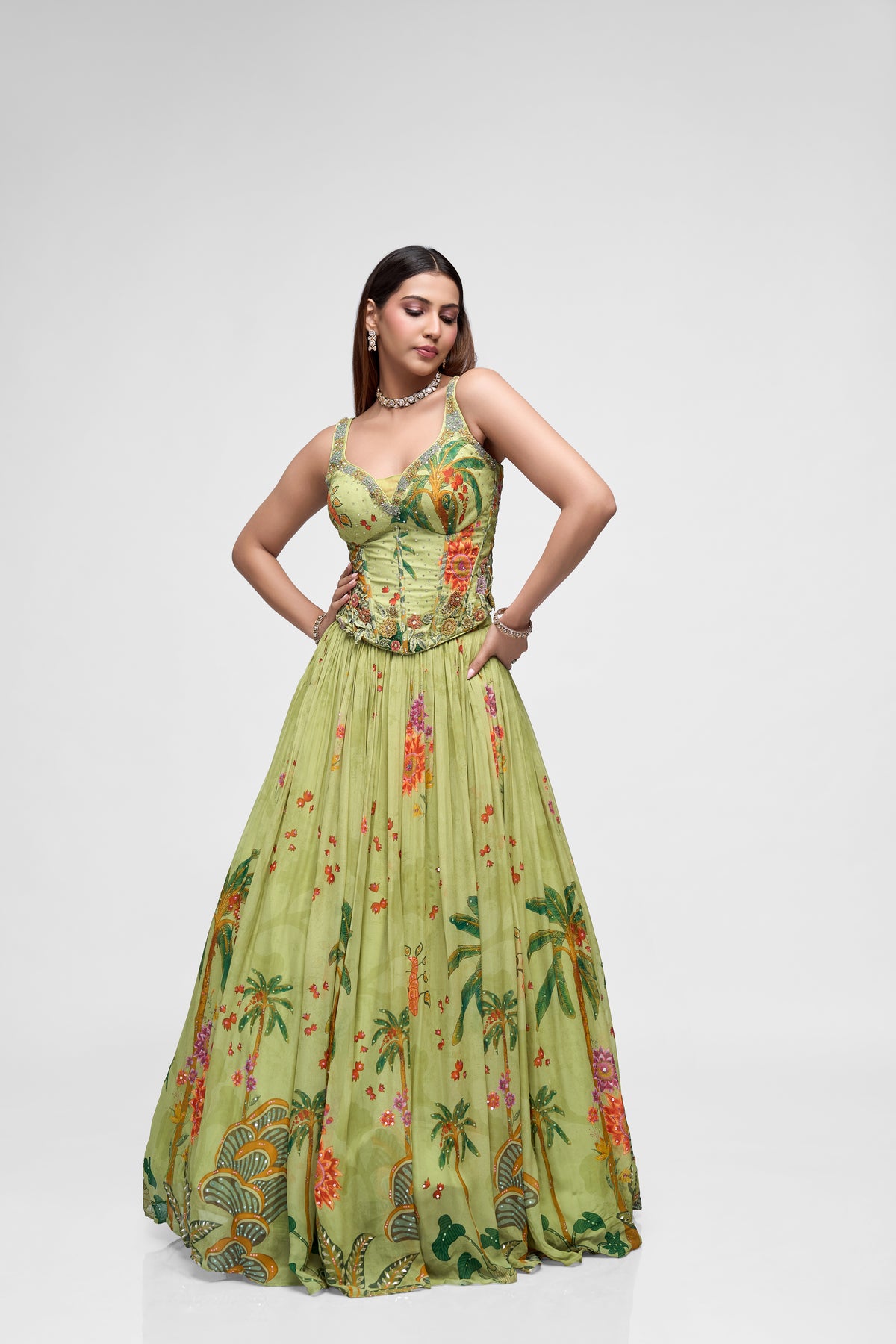 Front view of green printed lehenga choli featuring intricate floral embroidery and corset-style blouse for reception and engagement parties.